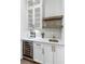 Wet bar with wine cooler, white cabinets, floating shelves, and modern herringbone backsplash at 2602 Drew Valley Ne Rd, Brookhaven, GA 30319