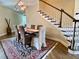 Dining area with a long wood table, six upholstered chairs, an ornate rug and staircase at 9602 Coastal Pointe Dr, Villa Rica, GA 30180