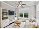 Cozy living room with built-in shelving, modern ceiling fan, and view to lush backyard at 2023 Yellow Finch Trl, Atlanta, GA 30316
