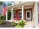 Charming front porch with brick pillars, white trim, a cozy red bench, and an American flag, creating a welcoming entrance at 3362 Palm Nw Cir, Kennesaw, GA 30144