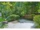 Private backyard features mature landscaping and a concrete patio at 5490 Chemin De Vie, Sandy Springs, GA 30342