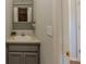Updated half bathroom featuring a gray vanity, decorative mirror, and adjacent doorway, offering convenience and style at 10 Stewart Hollow Ln, Covington, GA 30016