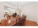 Dining room with long table and hardwood floors next to a living room area with a piano at 2722 Brookhaven Ln, Buford, GA 30518