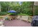 Wooden outdoor patio with a grill, dining table, and bench seating overlooking the yard at 2722 Brookhaven Ln, Buford, GA 30518
