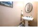 Elegant powder room with a pedestal sink, decorative mirror, and soft lighting, enhancing the home's charm at 13042 Dartmore Ave, Alpharetta, GA 30005