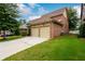 Brick home showcasing a two-car garage and a well-manicured lawn at 13042 Dartmore Ave, Alpharetta, GA 30005