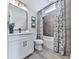 Bright bathroom featuring a white vanity, black fixtures, and shower with decorative patterned curtain and gray tiled walls at 158 South Village Ave, Holly Springs, GA 30115