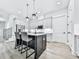 Bright kitchen boasts white cabinets, stainless steel appliances, an island with seating, and hardwood floors at 158 South Village Ave, Holly Springs, GA 30115