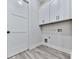 Bright laundry room with white cabinets, wood-look flooring, and modern washer/dryer hookups at 158 South Village Ave, Holly Springs, GA 30115