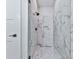 Luxurious shower featuring glass doors, a marble-patterned surround, and a built-in bench at 158 South Village Ave, Holly Springs, GA 30115
