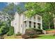 Charming two-story home with white siding, columned porches, landscaped yard, and mature trees at 1160 Foster Nw Pl, Atlanta, GA 30318