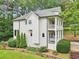Two story home showcasing gray siding, a double porch, green bushes, and a wooded background at 1160 Foster Nw Pl, Atlanta, GA 30318
