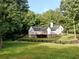 White two-story home surrounded by lush greenery and a black wooden fence at 128 Golden Hills Dr, Woodstock, GA 30189