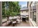 Outdoor deck area with dining table, chairs, and stainless steel grill with a green forested backyard at 2110 Timball Nw Rd, Atlanta, GA 30318