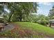 The green backyard features a spacious lawn, mature trees and a stone bench, perfect for relaxation at 1977 Wee Kirk Se Rd, Atlanta, GA 30316