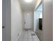Neutral-toned hallway with tiled flooring, a white door, and a glimpse into a room with a large, dark wood cabinet at 4135 Sunrise Trail, Atlanta, GA 30349