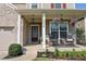 Inviting front porch with seating, hanging floral arrangements, black metal railings and manicured landscaping at 6298 Pierless Ave, Sugar Hill, GA 30518