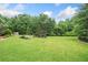 Expansive backyard featuring lush green lawn, mature trees, manicured landscaping, and a pond at 407 Maple Ridge Ct, Cumming, GA 30028