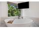 Close-up of the elegant freestanding bathtub with a view to a lush backyard at 407 Maple Ridge Ct, Cumming, GA 30028
