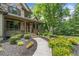 Charming stone-front home with a welcoming porch, lush landscaping, and a curved walkway at 407 Maple Ridge Ct, Cumming, GA 30028