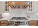 Close up of the kitchen stove featuring a decorative backsplash, custom hood, and marble countertops at 407 Maple Ridge Ct, Cumming, GA 30028