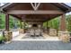 Inviting covered outdoor kitchen and dining area featuring stone counters, stainless grill, and a dark wood pergola at 407 Maple Ridge Ct, Cumming, GA 30028