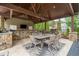 Inviting outdoor kitchen and dining area featuring stone counters, stainless grill, and a dark wood pergola at 407 Maple Ridge Ct, Cumming, GA 30028