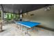 A covered patio features an outdoor entertainment area with a ping pong table, bar seating, and ceiling fans at 407 Maple Ridge Ct, Cumming, GA 30028
