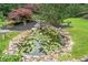 Beautiful pond featuring a small waterfall, lily pads, rock accents, and well-maintained landscaping at 407 Maple Ridge Ct, Cumming, GA 30028