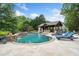 A luxurious backyard oasis features a custom-designed pool, covered outdoor kitchen, and comfortable lounge chairs at 407 Maple Ridge Ct, Cumming, GA 30028
