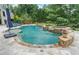 A stunning backyard features a freeform pool with stone accents, a waterfall feature, and mature landscaping at 407 Maple Ridge Ct, Cumming, GA 30028