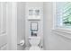 A half bathroom featuring a white toilet, a small cabinet and a window at 1945 Barrett Dr, Cumming, GA 30040