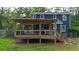 Backyard featuring a home with a deck with a pergola and lush green lawn surrounded by mature trees at 233 Oakridge Se Dr, Cartersville, GA 30121
