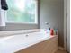 A relaxing, bright bathroom is highlighted with a stand alone soaking tub next to a nice bright window at 2430 Tribble Creek Cv, Grayson, GA 30017