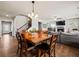 Open-concept dining room, featuring a dark wood table, pendant lighting, stairs to the upper level, and fireplace at 5730 Arbor Green Cir, Sugar Hill, GA 30518