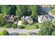 A high angle, bright aerial view shows several brick-clad homes nestled on well-manicured lawns with mature trees at 9310 Chapelwood Dr, Johns Creek, GA 30022