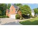Brick home featuring a two-car garage, well-manicured lawn, and lush landscaping at 9310 Chapelwood Dr, Johns Creek, GA 30022