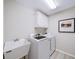 Laundry room with modern appliances, a utility sink, and a framed piece of art at 9310 Chapelwood Dr, Johns Creek, GA 30022