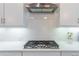 Close-up of a modern gas stovetop with subway tile backsplash and white cabinets at 1382 Doublegate Ne Dr, Atlanta, GA 30319