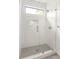 Close up of white tiled shower with glass door and transom window allowing natural light at 19 Moda Ln, Atlanta, GA 30316