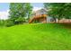Large backyard featuring lush green grass, mature trees, and a two-story house with a deck at 2045 Bethany Spring Trce, Cumming, GA 30041