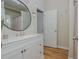 Bright bathroom featuring a vanity with white cabinets, a round mirror and hardwood floors at 2045 Bethany Spring Trce, Cumming, GA 30041