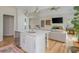 Open-concept kitchen with island, white cabinets, stainless steel appliances, and adjacent living room with fireplace at 2045 Bethany Spring Trce, Cumming, GA 30041