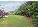 Spacious backyard with lush lawn, mature trees, a trampoline, and a fenced perimeter for privacy at 402 Homestead Dr, Dallas, GA 30157