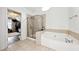 Bright bathroom featuring walk-in shower, jetted tub, and a door leading to a walk-in closet at 402 Homestead Dr, Dallas, GA 30157