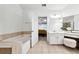 Bright bathroom featuring bath tub, vanity table with stool, and a door leading to a bedroom at 402 Homestead Dr, Dallas, GA 30157