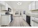 Well-lit kitchen with white cabinets, black appliances, and gray laminate flooring at 245 London Ln, Hiram, GA 30141