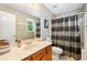 Neutral bathroom featuring a single vanity, large mirror, and tub with gray and black patterned shower curtain at 360 Glade Knoll Trail Trl, Fayetteville, GA 30215