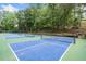 Two outdoor tennis courts with blue and green surface and wooded surrounding area, perfect for recreation at 545 Matterhorn Way Way, Alpharetta, GA 30022