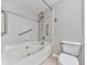 Well-lit bathroom featuring a built-in tub, tiled walls, and a toilet with a grab bar at 3334 Peachtree Ne Rd # 614, Atlanta, GA 30326